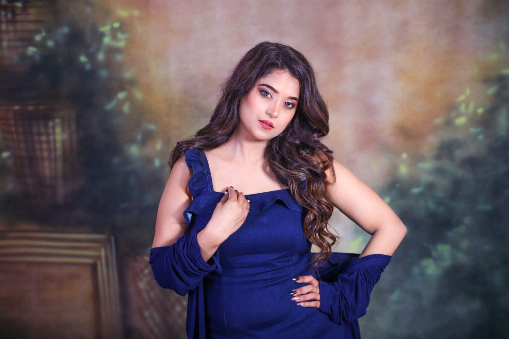 Studio portrait of a beautiful South Asian woman posing gracefully in a blue dress.
