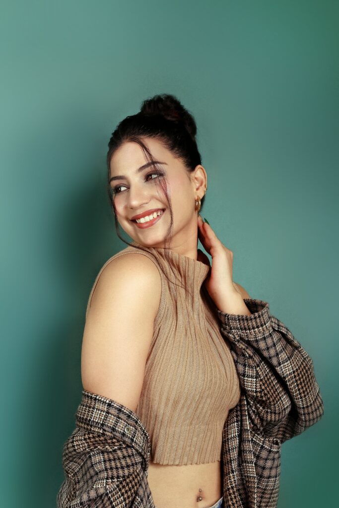 Portrait of a smiling woman in stylish clothing against a green background, captured in Indore, MP, India.