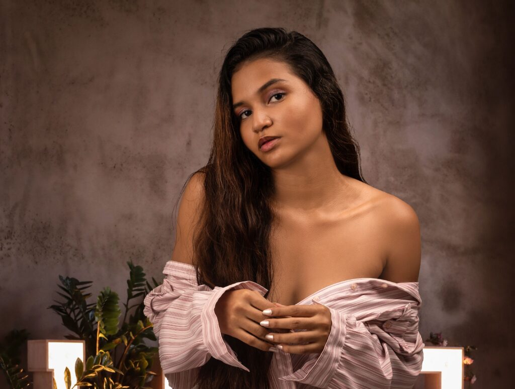 Beautiful woman in an off-shoulder top posing gracefully in a warm setting.